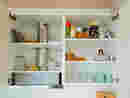 Geöffneter Küchen-Hängeschrank mit Tassen, Gläsern und Küchenutensilien