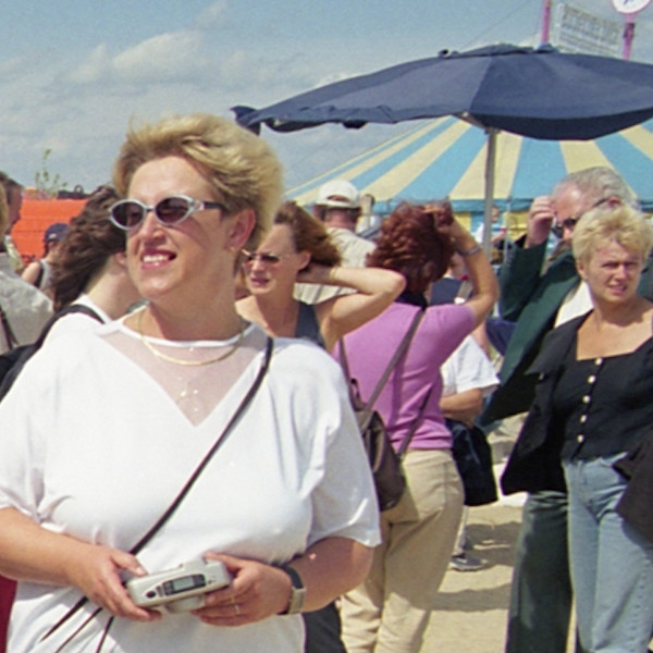 Frau mit Sonnenbrille am menschenbefüllten Strand